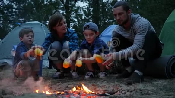 晚上在户外野餐美国家庭围着火准备黄色玉米妈妈孩子和爸爸视频的预览图