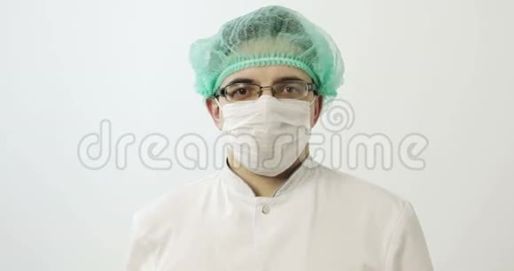 年轻的外科医生摘下面具和帽子视频的预览图