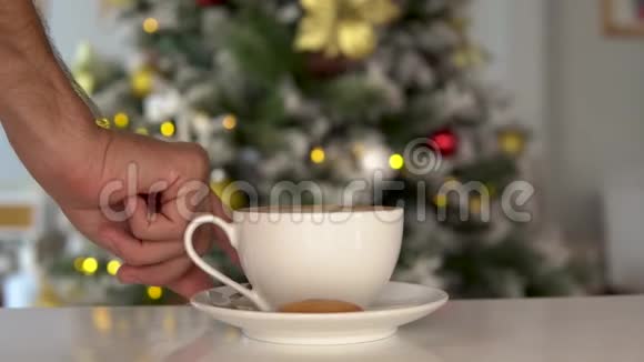 男人手搅动圣诞咖啡背景上的新年树视频的预览图