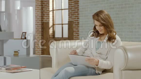 快乐的年轻女性使用平板电脑应用程序看着相机视频的预览图