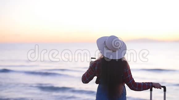 年轻的女游客在海边为日落或黎明拍照视频的预览图