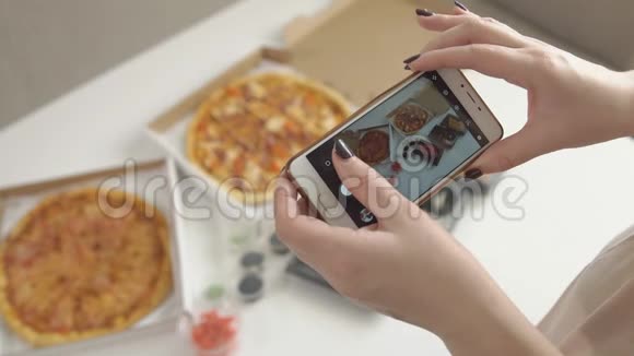手拿智能手机拍美味披萨的照片视频的预览图