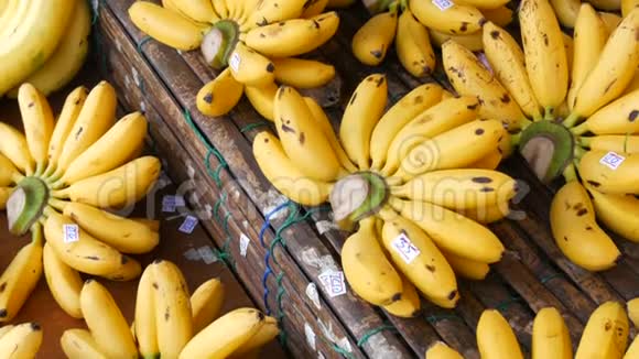 泰国街头市场的竹制柜台上挂着价格标签的漂亮的黄色小香蕉束视频的预览图