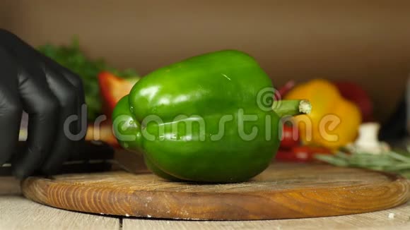 黑手套厨师拿着一个多汁的青椒它躺在木板上在一个木板上把它切成两等分视频的预览图