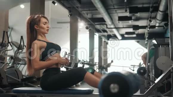 年轻的运动女性运动员在健身房的赛艇机上进行艰苦的锻炼美丽健康女性视频的预览图