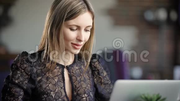 一位金发碧眼的美女在笔记本电脑上为女友挑选礼物她看着视频的预览图