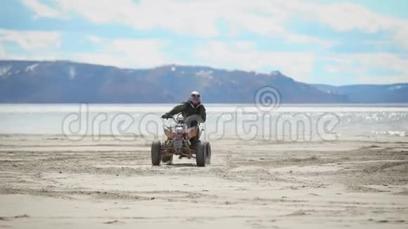 河岸海滩上天气晴朗一个人正骑着ATV在细沙上ATV上的赛车手执行视频的预览图