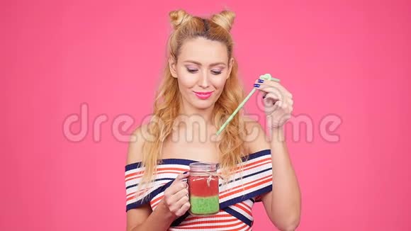 年轻女子手里拿着一个杯子上面有粉色背景的冰沙视频的预览图