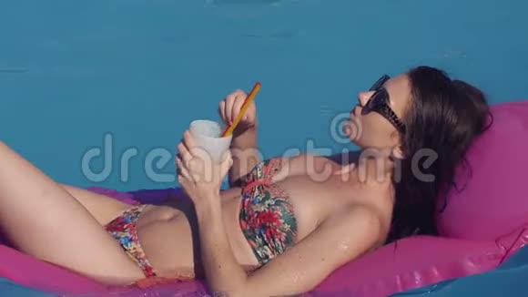 美丽的年轻女子在夏天在游泳池放松躺在充气休息室在阳光夏季时间她是视频的预览图