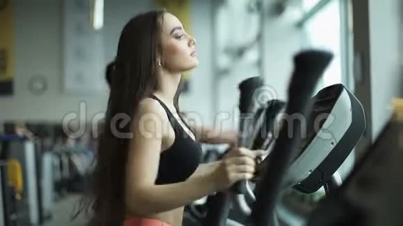 年轻的健康女性在健身中心使用椭圆教练视频的预览图