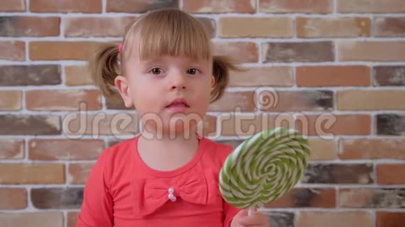 可爱的小女孩和大的绿色棒棒糖孩子吃甜食视频的预览图