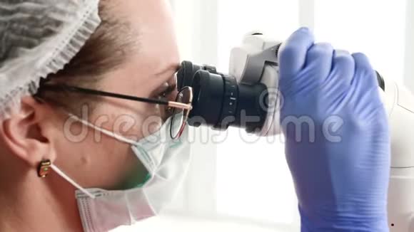 一位戴眼镜的妇女带着一位专业的牙医在她的口腔显微镜下工作视频的预览图