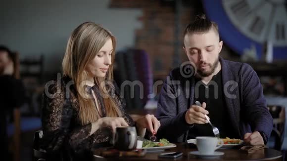 一对年轻夫妇在餐馆里吃沙拉一个男人和一个漂亮的女人在吃饭时说话桌子上有几杯视频的预览图