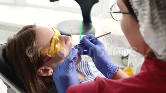 那个戴着黄色防护眼镜的漂亮金发女孩检查了她张开的嘴女性牙医检查视频的预览图
