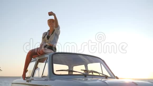 在旧机上用手机拍摄的女性背景天空年轻女性的自照复古车视频的预览图