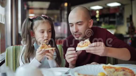 爸爸和一个小女儿在披萨店吃披萨不健康的食物吃快餐视频的预览图