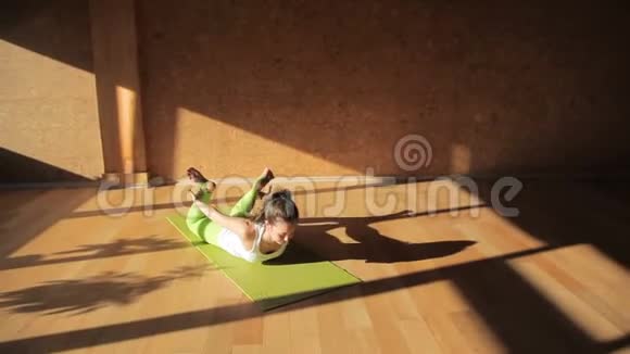 一位女运动员伸展双腿背部躺在运动垫上视频的预览图