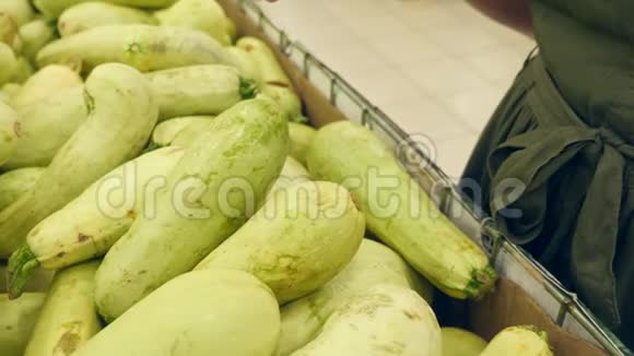 一个女人在蔬菜货架上的超市里买蔬菜和水果人类选择西葫芦慢动作4k视频的预览图