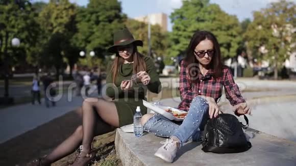 公园里的两个女孩在吃三明治和聊天视频的预览图