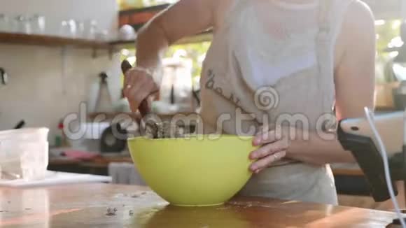 年轻女子在绿色塑料碗里揉面包视频的预览图