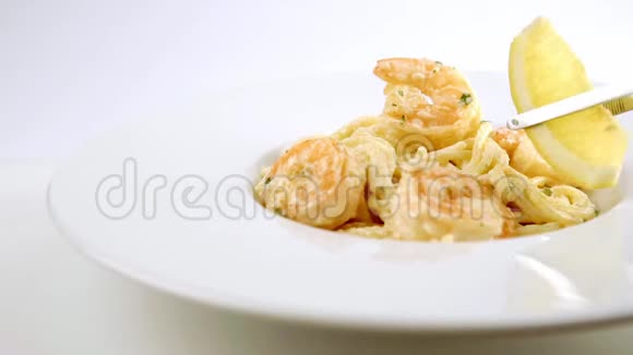 用柠檬装饰的白色盘子上有虾的意大利面条视频的预览图