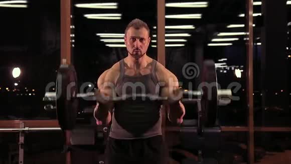 一个肌肉发达的运动员在健身俱乐部里用杠铃锻炼身体视频的预览图
