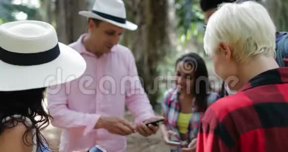 使用手机智能手机聊天的背包人群男人和女人在热带棕榈旅行时观看照片视频的预览图