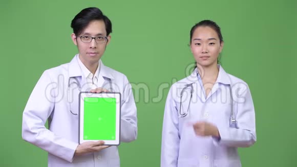 年轻的亚洲夫妇一起展示数字平板电脑视频的预览图