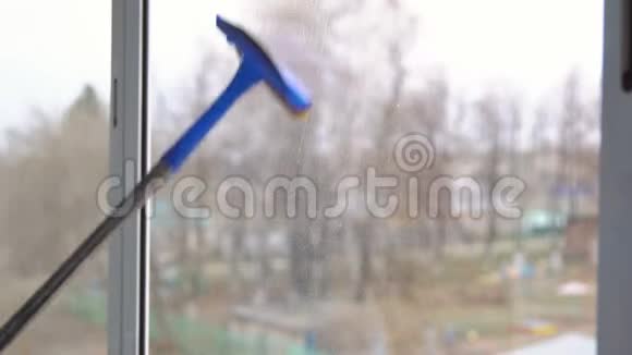 年轻女子用橡皮拖把擦窗户视频的预览图