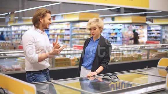 快乐的白种人夫妇在购物中心的杂货店选择冷冻食品视频的预览图