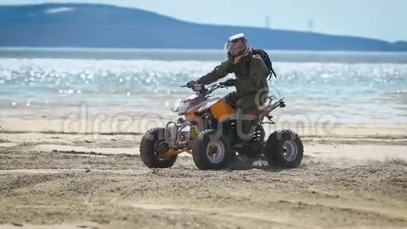 一个戴着头盔的人骑着ATV在海边的沙滩上一个人很快地转过身来视频的预览图