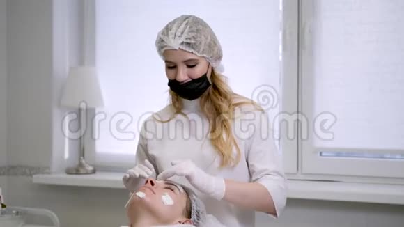 戴橡胶手套的美容医生在脸上涂霜视频的预览图