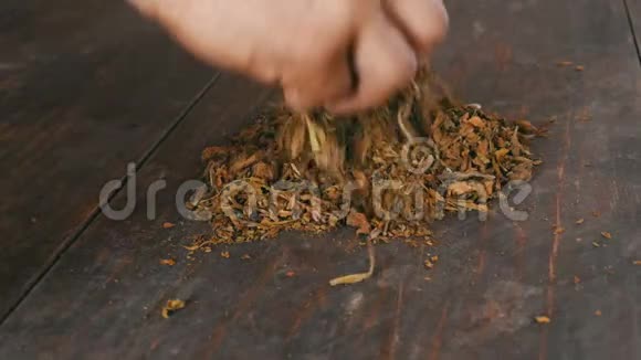 男性双手揉碎桌子上干燥的烟叶视频的预览图