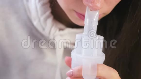 使用雾化器和吸入器进行治疗年轻女性通过鼻吸器喷嘴吸入特写鼻子视频的预览图