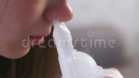 使用雾化器和吸入器进行治疗年轻女性通过鼻吸器喷嘴吸入特写鼻子视频的预览图