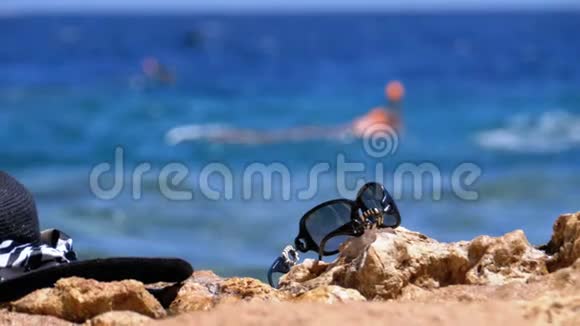 埃及海滩上的帽子和眼镜架在海边的岩石上视频的预览图