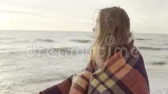 迷人的黑发女人站在海边做梦年轻的女性享受海滩在寒冷的日子里挥手视频的预览图