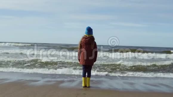 快乐的孩子站在海边眺望远方微笑的小女孩从波浪中逃跑微笑着视频的预览图