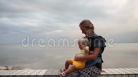 金发的孩子在海滨从母亲的怀抱中下来视频的预览图