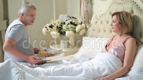 老人在床上为妇女提供早餐视频的预览图