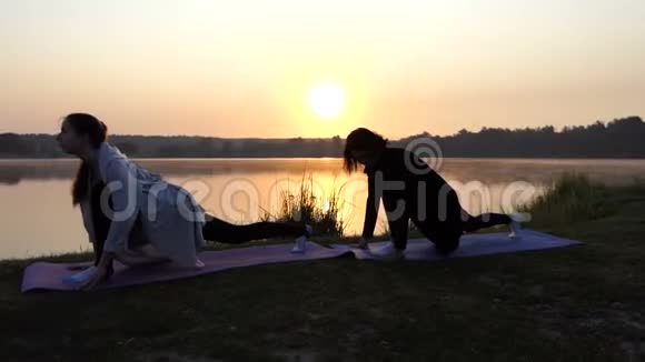 两个女人站在猫上在日落时伸展前进的动力视频的预览图