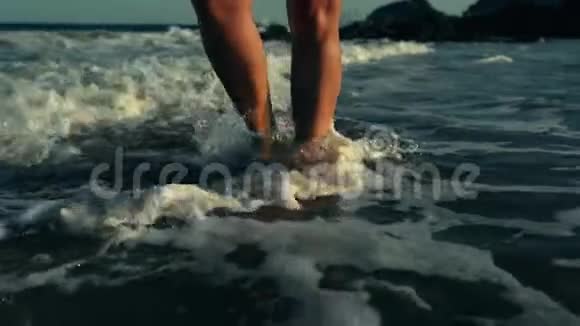 女性的腿在水波上行走苗条的女性腿在沙滩上移动视频的预览图