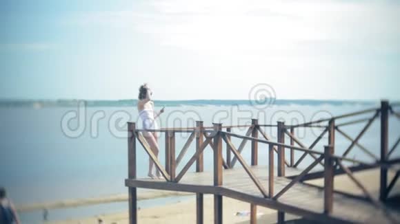 热辣的女孩站在沙滩上的桥上晒太阳4k视频的预览图