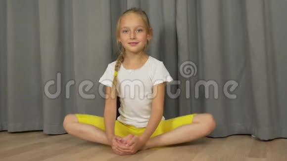 年轻女孩做瑜伽蝴蝶姿势白姑娘在室内客厅伸懒腰视频的预览图