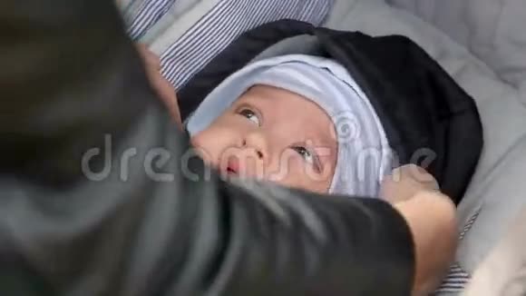 妈妈纠正孩子躺在婴儿车里的暖和的衣服视频的预览图