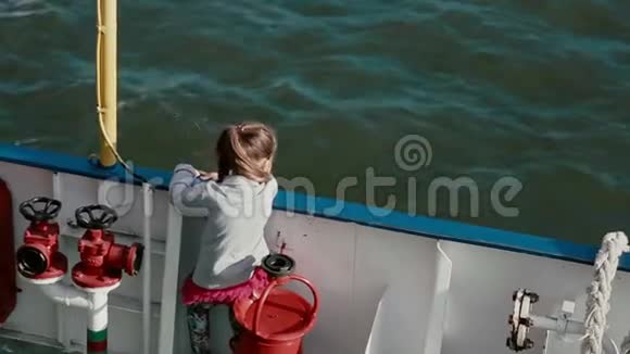 一个小女孩正紧紧地站在船甲板看着水视频的预览图