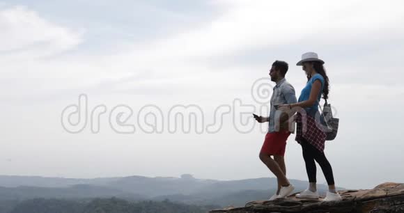 一对从山顶看风景的游客一对年轻男女的旅行视频的预览图