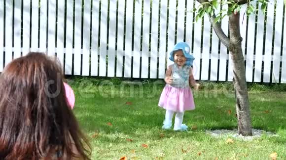 一个漂亮的一岁女孩戴着一顶太阳帽和一件华丽的裙子静静地走向她的母亲在夏天在视频的预览图