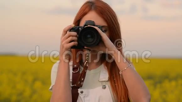 一位年轻的女摄影师在盛开的田野里拍照微笑着视频的预览图