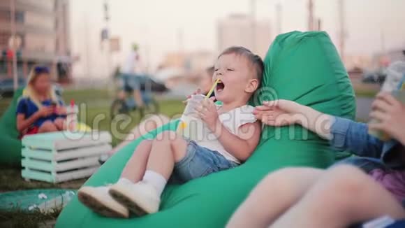男孩和女孩哥哥和姐姐在公园里消磨时间坐在包椅上喝水跳舞笑视频的预览图